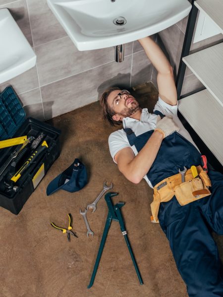 high-angle-view-of-young-male-plumber-fixing-sink-in-bathroom.jpg
